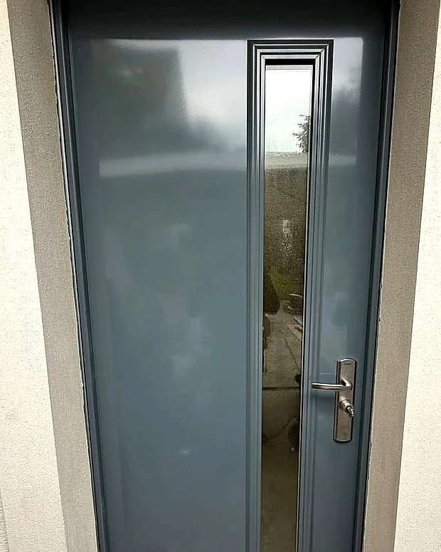 Porte d'entrée de pavillon gris anthracite à vitrage vertical, posée sur une façade enduite